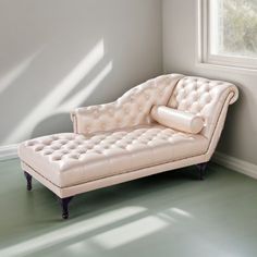 a white chaise lounger sitting in front of a window on a green floor