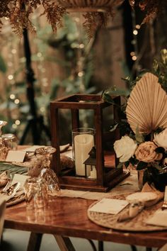 a wooden table topped with a lantern filled with white flowers and greenery on top of it