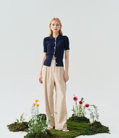 a woman standing on top of a moss covered ground with flowers and plants around her