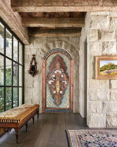 an entryway with stone walls, wood floors and a wooden bench in the center