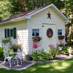 a small white house with flowers and potted plants