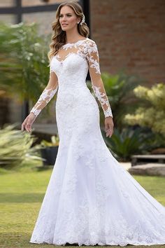 a woman in a white wedding dress standing on the grass with her arms around her waist