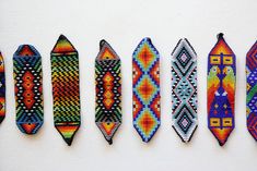 six different colored ties are lined up on a white surface, each with an individual's own design