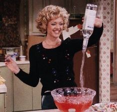 a woman is pouring something into a glass on the counter in front of a bowl