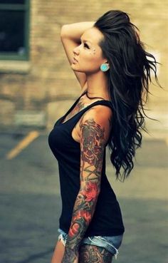 a woman with tattoos on her arm and leg is standing in the parking lot looking off into the distance