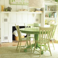 a green table and chairs in front of a fireplace with bookshelves on the wall