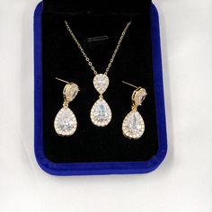 This Yellow Gold Crystal Bridal Jewelry Set offers a touch of sophistication for the discerning bride on her wedding day. This opulent collection presents teardrop-shaped cubic zirconia earrings that catch the light with every turn, a necklace that glistens with each movement, and a bracelet that adds a finishing sparkle to the ensemble. The earrings, with their elegant teardrop form, are crafted to accentuate the bride's visage, while the necklace's adjustable design ensures it drapes just righ Elegant Crystal Bridal Sets For Marriage, Elegant Jewelry For Marriage With Matching Earrings, Gold Cubic Zirconia Bridal Accessories For Wedding, Elegant Gold Jewelry For Brides, Gold Cubic Zirconia Bridal Accessories For Gift, Elegant Cubic Zirconia Jewelry For Wedding Gift, Gold Cubic Zirconia Bridal Accessories As Gift, Gold Cubic Zirconia Wedding Jewelry, Elegant Gold Hand Set Bridal Accessories