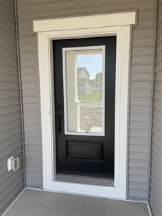 a black front door on a gray house with white trim and sidelights, in the day light