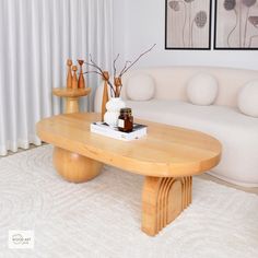 a living room with a white couch and coffee table in front of two paintings on the wall