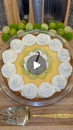 a pie with white frosting and limes in the middle on a wooden table