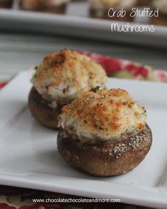 two stuffed mushrooms on a white plate with parmesan cheese and herbs sprinkled on top