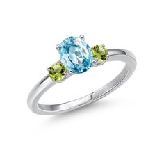 an oval blue topazte ring with two green gems on the sides and a white gold band