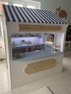 a doll house with the door open and shelves on both sides that are filled with food