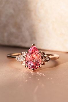 a pink diamond ring sitting on top of a table