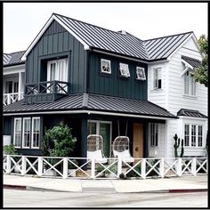 a black and white house with lots of windows on the second floor is next to a fence