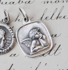 These are two little guardian angel good luck charm pendants made of antique sterling silver around 1910-1940s. Please chose one from the options. They both have antique Hungarian hallmarks for silver.  1. SOLD Round, with 4 forget me not flowers around the angel, 20 x 14 mm, there is a bit of wear on it, please enlarge to see, 2. Rounded down square shape pendant 22 x 14 mm, the larger one, WAS 49 USD!  3. ONE SOLD, buy both, discounted!  A very unusual and rare piece to add to your collection of pendants!  Please check out my other items too, I hope one of them has your name on it! RESERVE: I offer 3 day reserve, if you need a little bit more time to make a payment, but you do not want someone else snatching up an item you have fallen in love with!  Jewelry can develop patina over time a Angel Necklace, Angel Pendant, Luck Charm, Luck Charms, Choose One, Guardian Angel, Good Luck, Charm Pendant, Jewelry Necklace Pendant