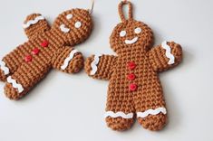 two crocheted gingerbreads hanging from strings on a white table with other items