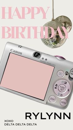 a digital camera sitting on top of a white table next to a happy birthday sign