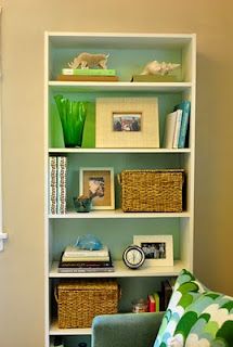 a living room with a green chair and white bookcase