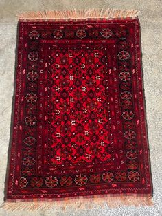 an old red rug with fringes on the bottom and sides is laying on the floor