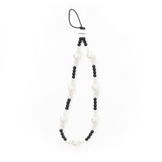 a black and white beaded necklace with pearls on the end, hanging from a cord