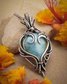 This stunning 23 carat genuine Larimar pendant is a must-have for any jewelry collection. The blue stone is beautifully accented by the intricate silver wire wrapping. Perfect for adding a touch of elegance to any outfit, this necklace is sure to turn heads wherever you go. D E T A I L S: 🌸 Genuine 23 carat Blue Larimar gemstone wire wrapped by hand. 🌸 Pendant height is 2 1/4 inches tall, and it is 1 inch wide. 🌸 The wire is SOLID .925 Sterling Silver (not silver plated). Sterling silver is also known for its durability and hypoallergenic properties, ensuring that this pendant will be a cherished piece for years to come. 🌸 The pendant comes on 22-inch sterling silver adjustable chain. Yes, make this necklace longer or shorter as you please! The pendant is not attached to the chain, so Wire Wrapped Pendant Tutorial, Wired Pendants, Paper Flower Crown, Hand Pendant, Blue Charm, Pendant Tutorial, Pendant Necklace Silver, Larimar Pendant, Wire Work Jewelry