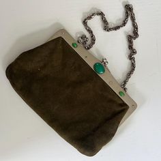 A fabulous circa 1910s, arts and crafts style evening bag with green cabochon trim. The bag features: - a silver toned metal frame with gentle sloped top and chain handle  - the frame is decorated with a large oval green cabochon that is flanked with two smaller cabochon  - the bag is made from a dark olive green fabric that feels like chamois leather  - inside the bag is lined with what feels to be chamois leather and there is a pocket - the bag fastens with a good strong kiss lock Label: None. Olive Green Fabric, Bag Art, Dark Olive Green, Craft Bags, Green Fabric, Clutch Handbag, Evening Bags, Purses And Handbags, Art Nouveau