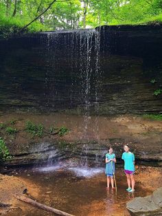 two children are standing in front of a waterfall