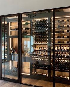 a room filled with lots of bottles of wine on the wall next to a table and chairs