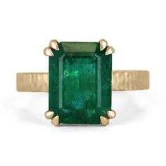 This 4.45-carat natural emerald cut emerald from Zambia is a showstopper. The emerald is cut in a classic emerald cut style, which shows off the stone's clarity and depth of color. The emerald is set in a unique four-double claw prong setting, which adds a modern twist to the classic style. The band of the ring is finished in matte hammered gold in 18K, which gives it a rustic and organic feel. The gold finish provides a beautiful contrast to the deep green of the emerald and adds a touch of warmth to the piece. Setting Style: Prong - Solitaire Setting Material: 18K Yellow Gold Setting Weight: 6.5 Grams Main Stone: Emerald Shape: Emerald Cut Weight: 4.45-Carats Clarity: Semi-Transparent Color: Rich Dark Green Luster: Very Good Treatments: Natural, Oiling Origin: Zambia Estimated Retail Val Emerald Size Chart, Emerald Cut Solitaire Ring, Emerald Solitaire Ring, Emerald Set, Emerald Gem, Solitaire Setting, Claw Prong, Colombian Emeralds, Minimalist Gifts