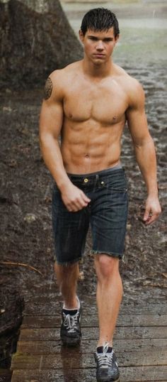 a shirtless man walking across a wooden bridge in the rain with no shirt on