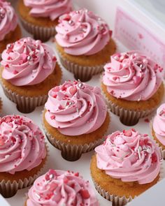 cupcakes with pink frosting and sprinkles in a white box