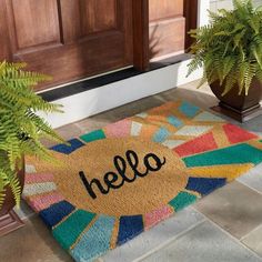 a welcome mat with the word hello on it next to potted plants in front of a door