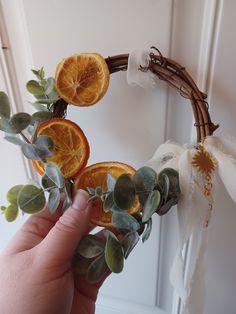 a hand is holding an orange slice wreath