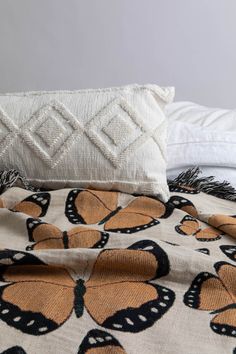 a bed topped with pillows and blankets covered in butterfly print on top of each other