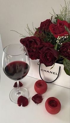 a glass of red wine next to some roses