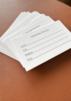 five envelopes sitting on top of a brown leather case next to a pen and pencil