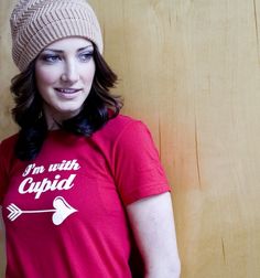 a woman wearing a red shirt with an arrow on the front and i'm with cupid on the back