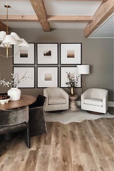 a living room filled with furniture and framed pictures on the wall above a wooden table