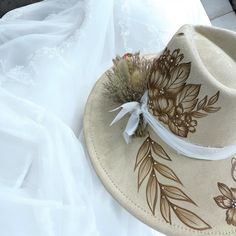 Burned Wide Brim Bridal focused Hat in Antique Beige, but also available in other shades of white. This Hat is burned using pyrography techniques. Embellishments with Rhinestones used for some bling and brightness. Dried Flowers and chiffon ribboning for the band details. Add your Date, initials and anything else youll want on your Forever Hat. Hats Boho Bridal, Dried Flowers Hat Band, Luxury White Elegant Hat Bands, Custom Adjustable Wedding Hats, Bohemian Wedding Hat With Adjustable Fit, Bohemian Adjustable Wedding Hat, Pyrography Techniques, Velvet Hat, October 5