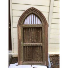 an old wooden door in front of a house with snow on the ground and behind it