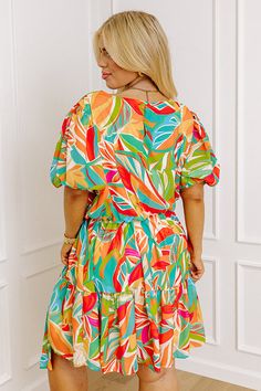 - Book a ticket to the tropics with this beautiful mini dress! - Fully lined Lightweight material with a colorful abstract botanical print - A crew cut neckline with back button closure and a keyhole detail - Short puff sleeves with smocked cuffs - A stretchy elastic waistline with a removable tie closure belt - A flowy yet flattering silhouette that ends in a ruffled hemline Tropical Multicolor Mini Dress For Vacation, Multicolor Mini Dress With Abstract Print For Vacation, Casual Mini Dress With Abstract Print For Vacation, Beach Dresses With Abstract Print In Mini Length, Tropical Printed Mini Dress For Beach, Tropical Print Mini Dress For Vacation, Multicolor Hawaiian Dress With Tropical Print, Tropical Vacation Mini Dress With Tropical Print, Hawaiian Style Multicolor Tropical Print Dress