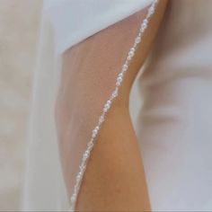 the bride's veil is draped over her shoulder and has a beaded edge