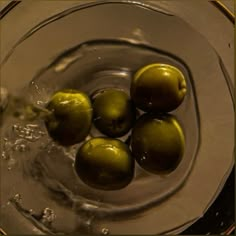 four green apples in a glass bowl with water