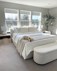 a large white bed sitting in a bedroom next to two windows