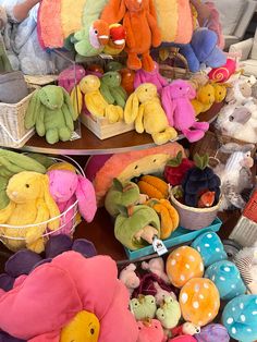 there are many stuffed animals in baskets on the table and one is holding a teddy bear