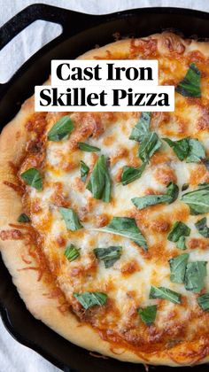 a pizza sitting in a black pan on top of a white tablecloth with green leaves