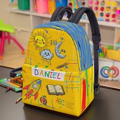 It's not just a backpack, it's a companion for your child's school adventures. Make school days special with this Personalized Unisex Elementary/Kindergarten Backpack! Perfect for young students, this backpack features cheerful illustrations of the sun, moon, rocket, and more, and can be customized with your child's name. The backpack is spacious with roomy compartments, a front pocket, and side pockets for water bottles, providing ample space for books, snacks, and school supplies. Adjustable padded shoulder straps ensure comfort, and the unisex design makes it suitable for both boys and girls. Designed by Bright Street. 🎁 Perfect for Gifts: Ideal for birthdays, back-to-school, and more!  Order now and give your child a backpack that's as unique and special as they are! Kindergarten Backpack, Canvas Rucksack, Make School, Personalized Backpack, Boys Backpacks, Preschool Kids, Canvas Backpack, Girls Toddler, Custom Bags