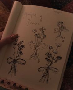 someone is holding an open book with flowers drawn on it and the pages are lined up