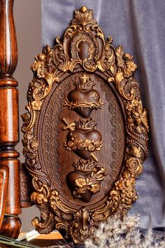 an ornate wooden frame with carved animals in the center on a table next to some feathers